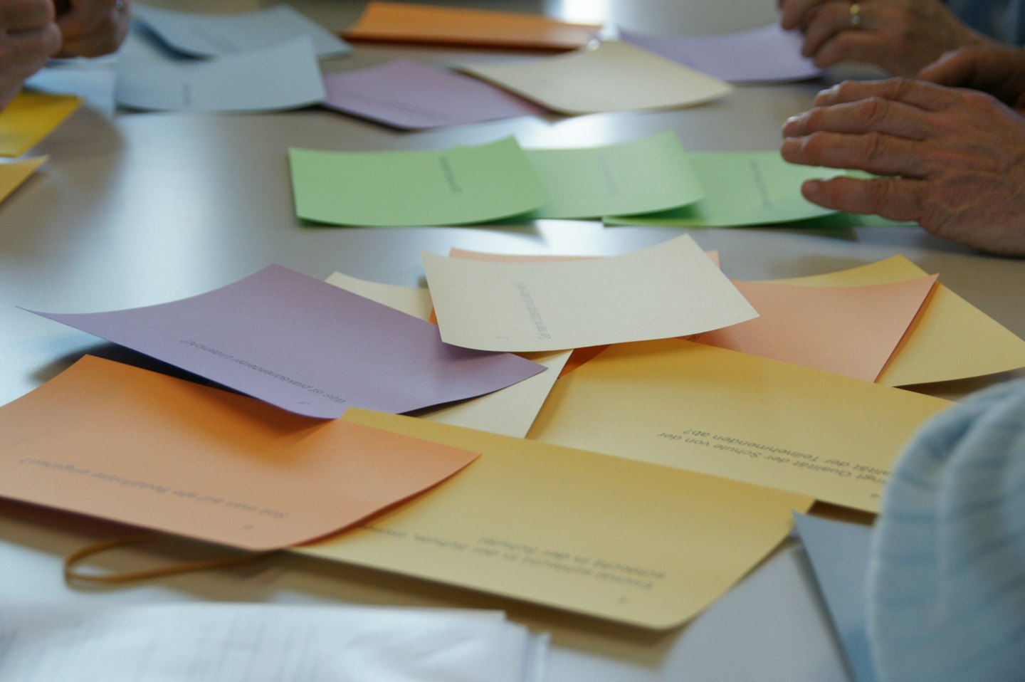 People arrange cards with German text on a workshop table.